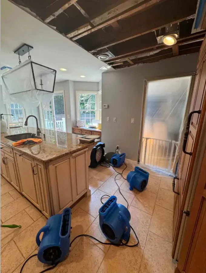 Air movers drying a kitchen floor after a water leak